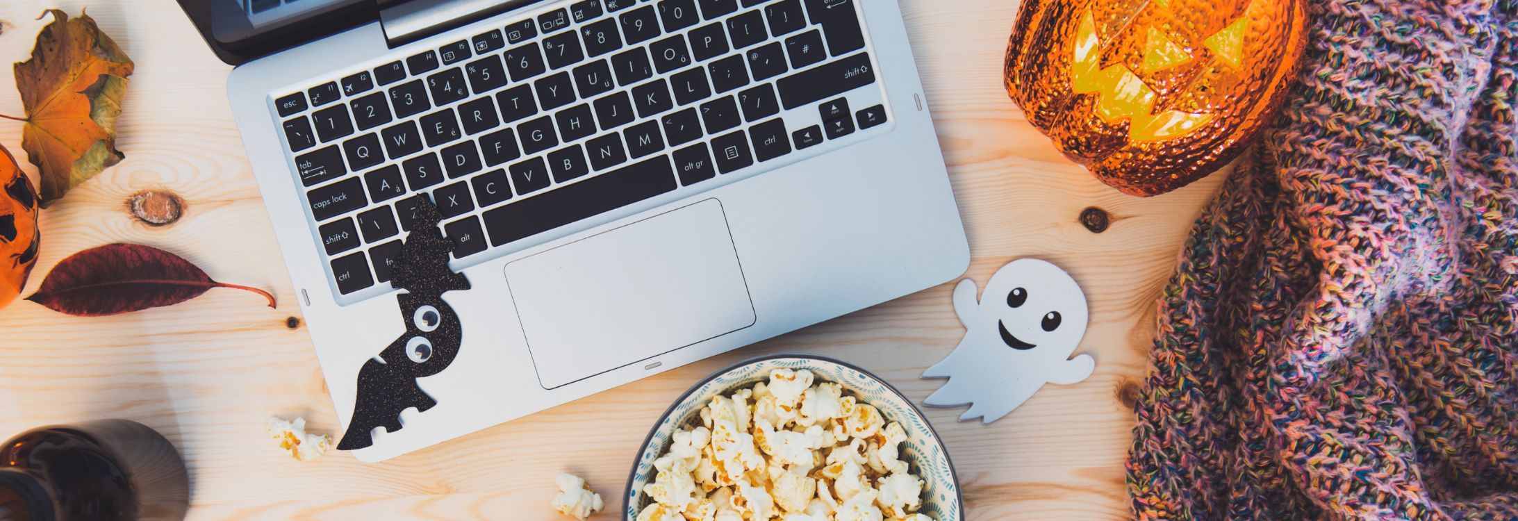 Laptop with Halloween themed decor & snacks - Halloween Movie Night Snacks blog cover
